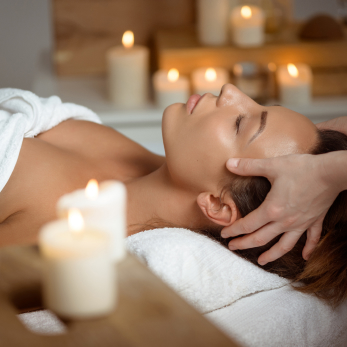 woman being given a facial surrounded by candles